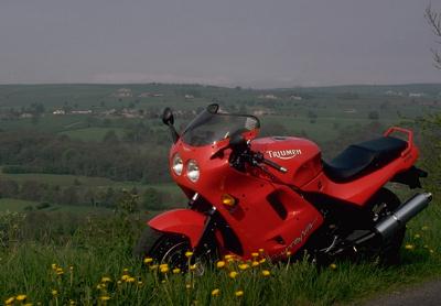 Photograph of very
                        red Triumph Daytona 1200 in green countryside
                        nerar Pateley Bridge